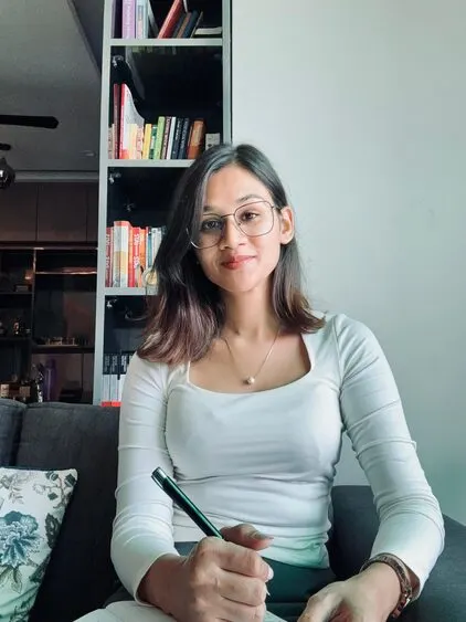 Psychiatrist in Delhi consulting with a patient, sitting in a modern office with bookshelf, writing notes during a session
