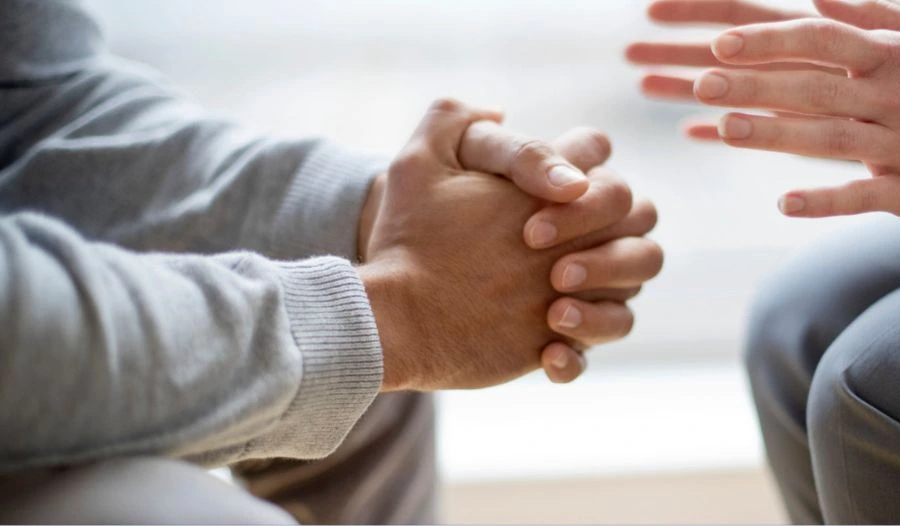 Clasped hands during a DBT session in India, focused on distress tolerance and emotional regulation.