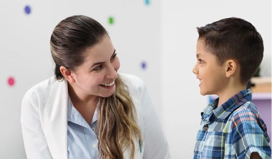 Friendly child psychologist in India engaging with a young patient in a colorful clinic setting.