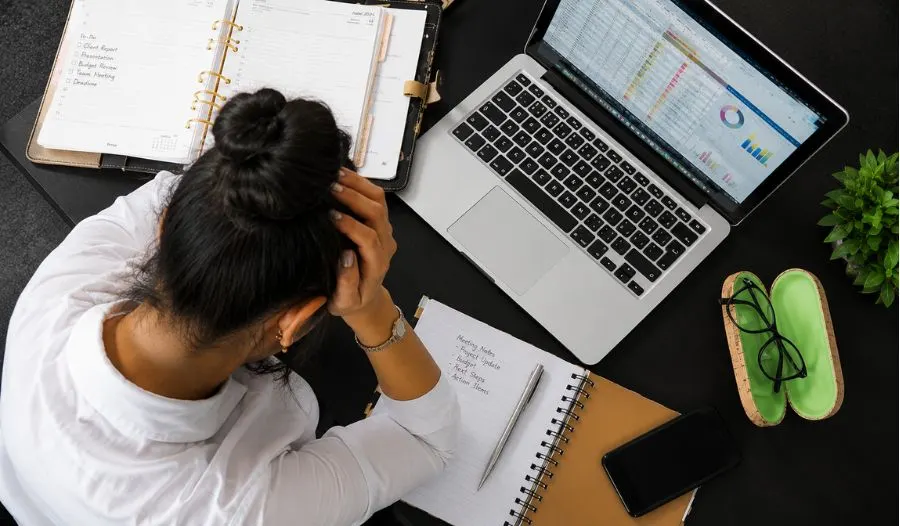 Professional woman feeling overwhelmed while working at her desk.