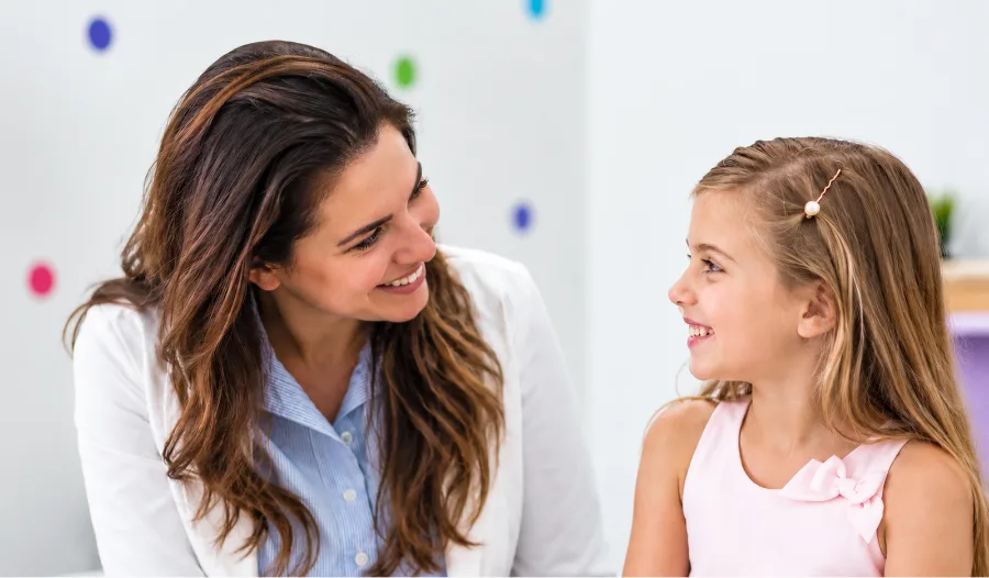 A child psychiatrist smiling warmly at a young girl during a clinical session.